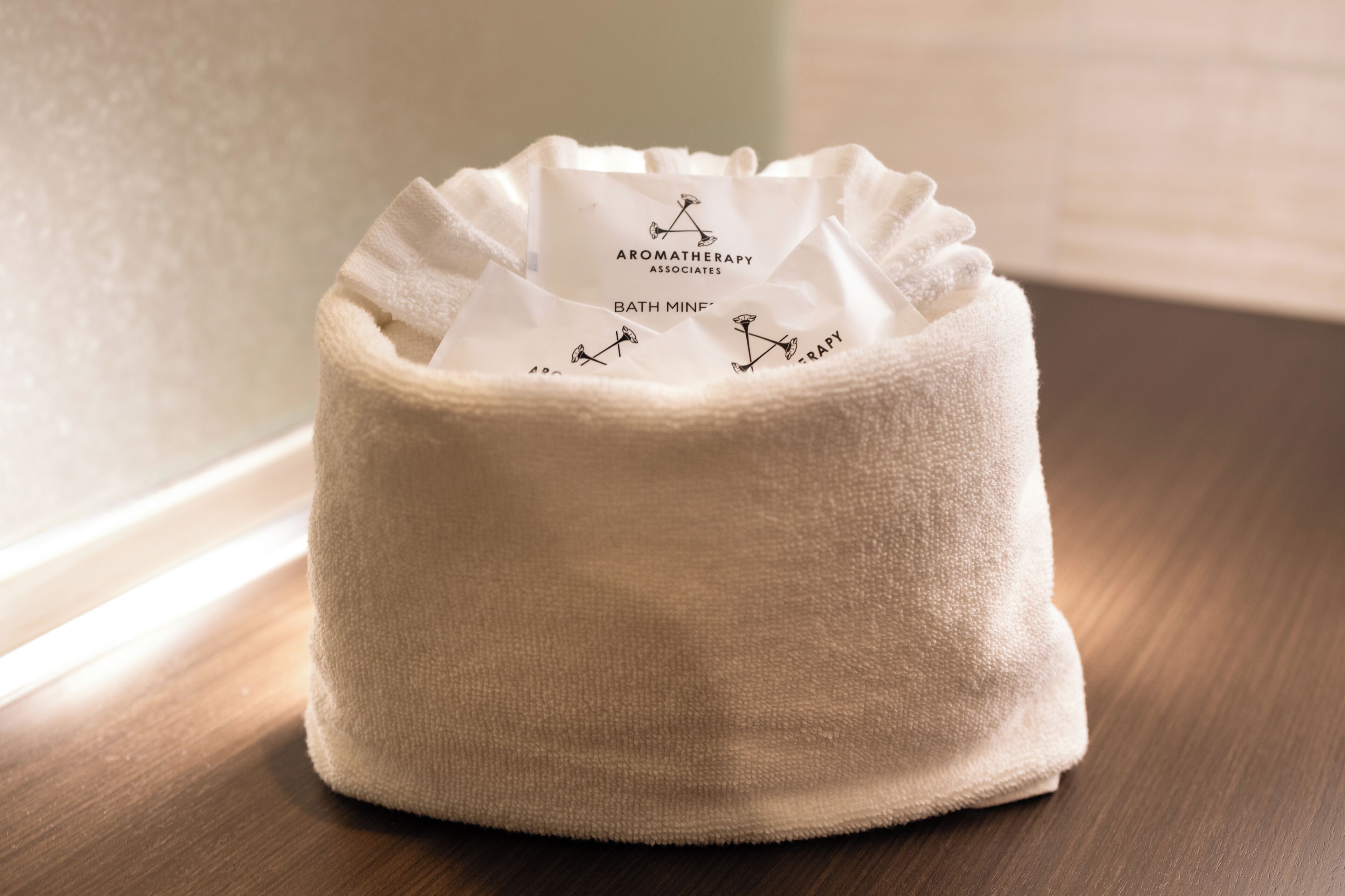 A white, textured bath mat with a label reading 'Aromatherapy Associates Bath Mine.'
