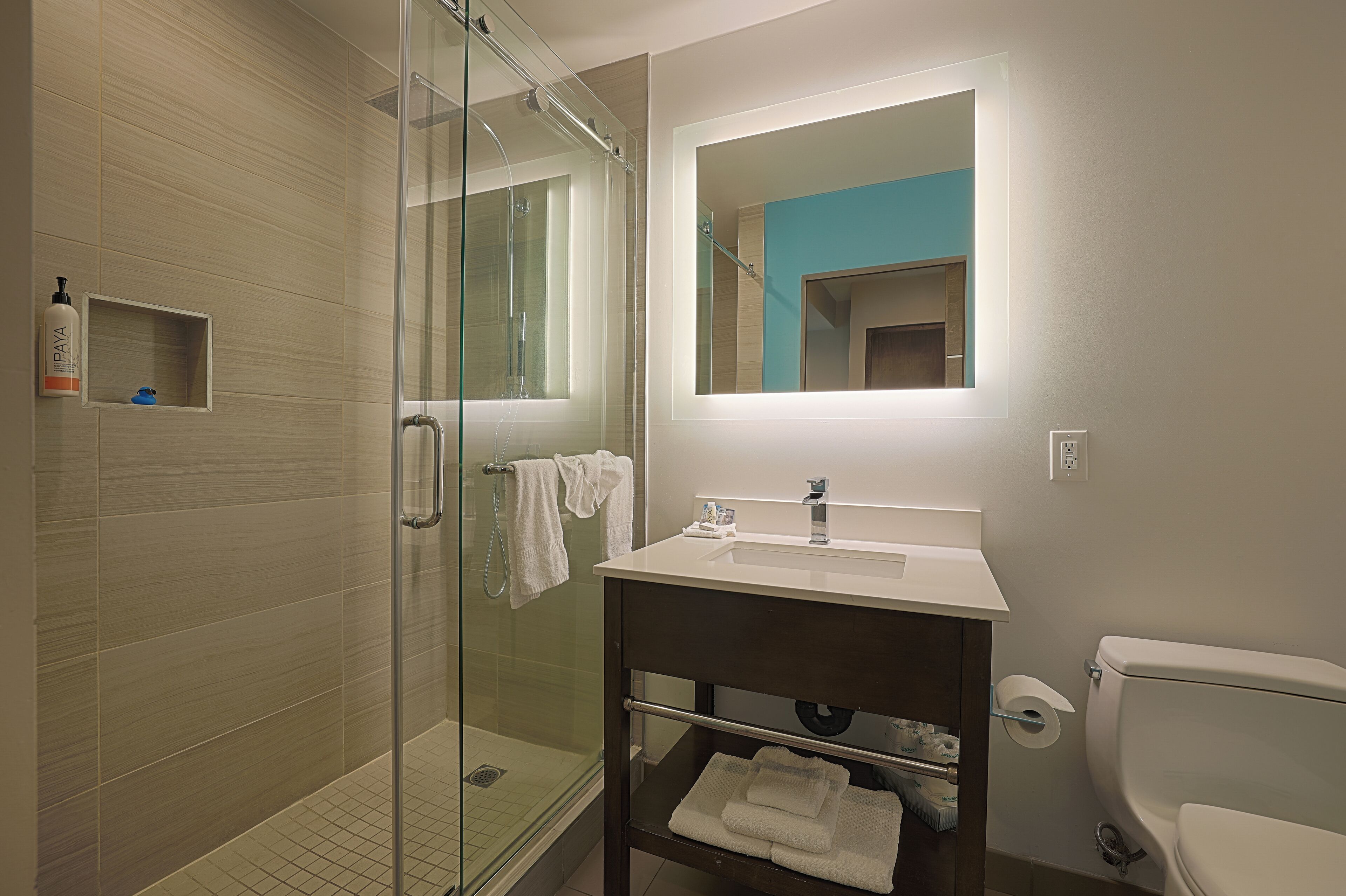 A modern bathroom with a glass shower enclosure, a white sink with a mirror above, and a toilet.