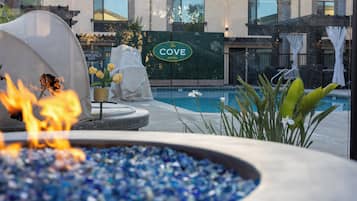 Un área de piscina con un letrero que dice 'The Cove Hotel', una chimenea decorativa y algunas plantas.