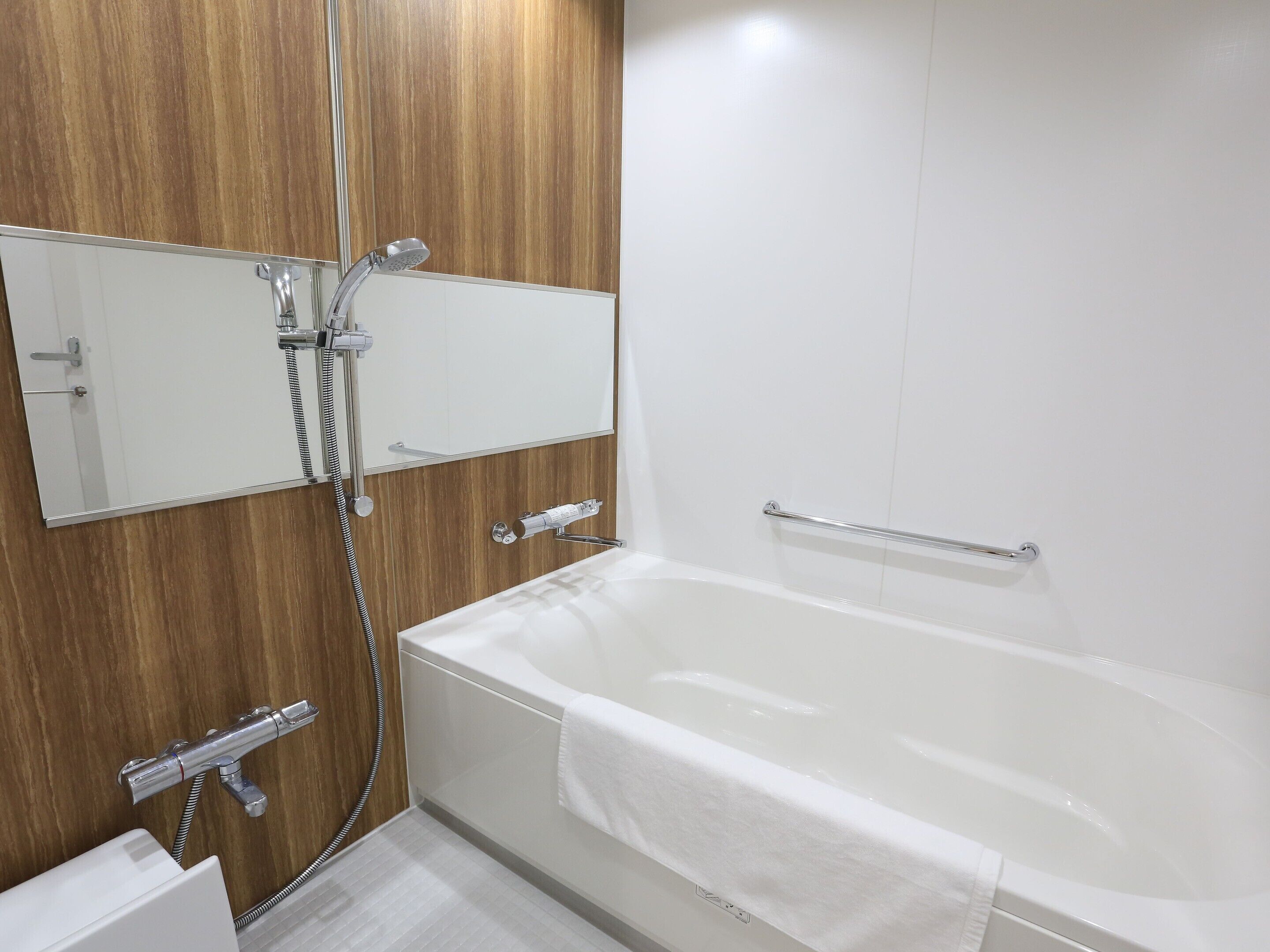 A modern bathroom with a bathtub, a shower, and a mirror.