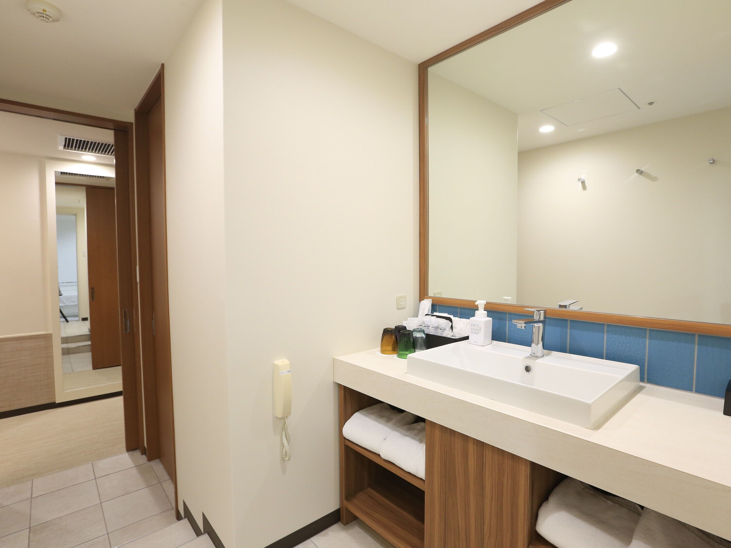 A hotel bathroom with a large mirror, a sink, and a towel rack.