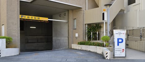 Entrada de un hotel con un letrero de estacionamiento, una escalera e indicación de la entrada.