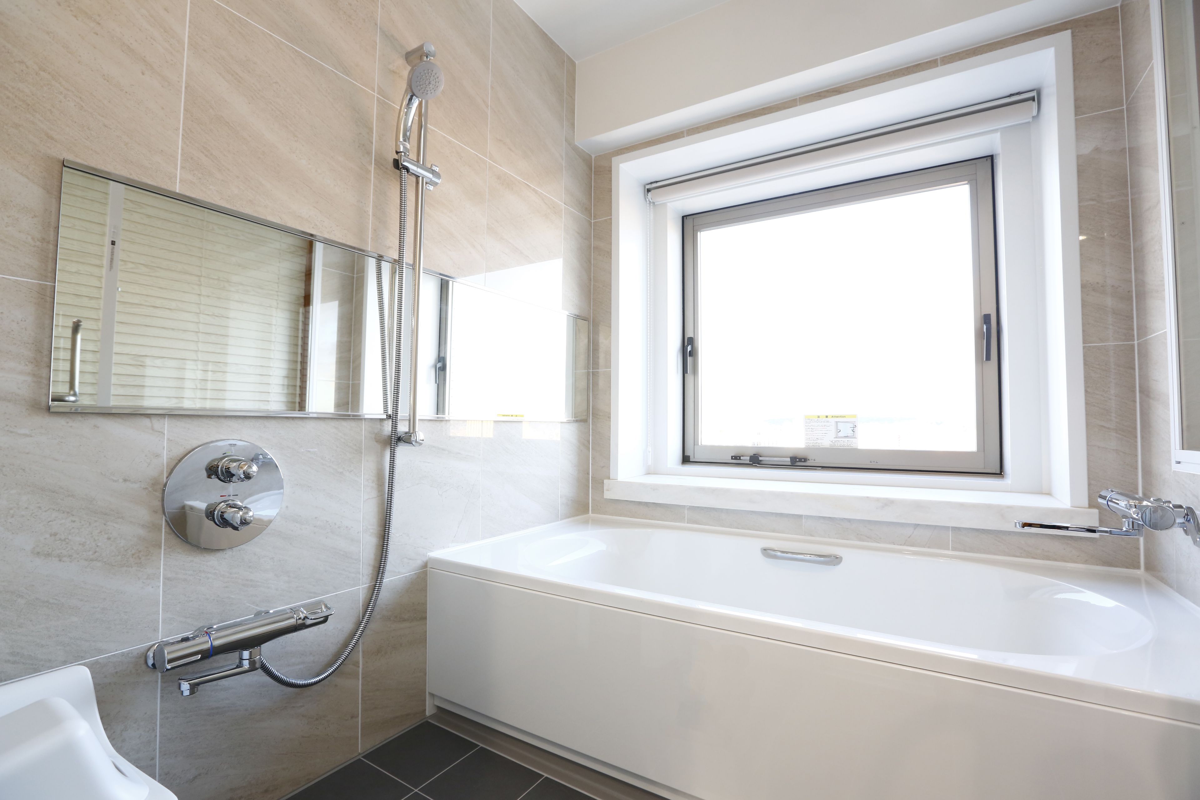 Un baño moderno con una bañera grande, ducha, inodoro y ventana que proporciona luz natural.