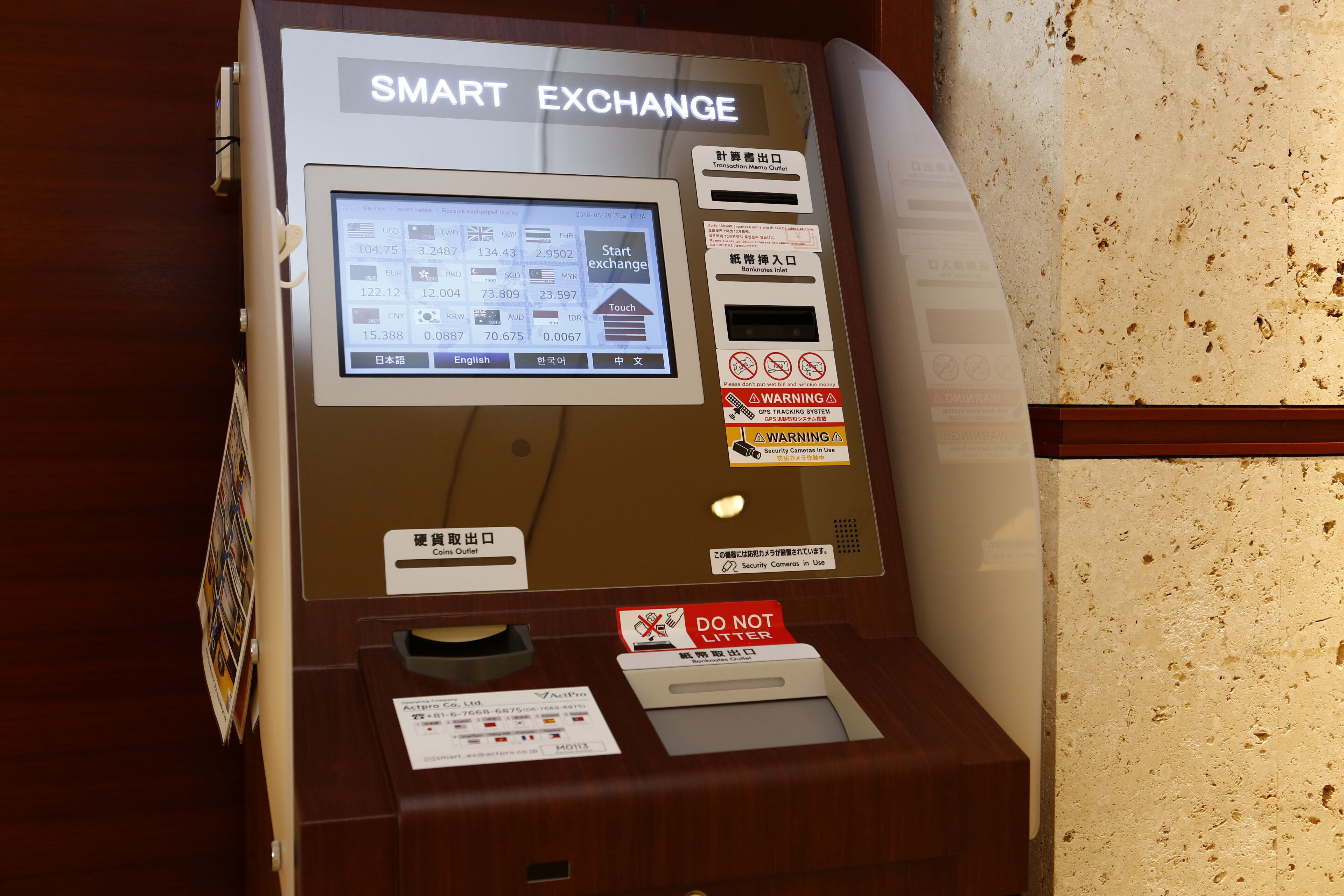 Un distributeur automatique intelligent doté d’un écran numérique, de boutons de sélection des devises et d’un lecteur de cartes.