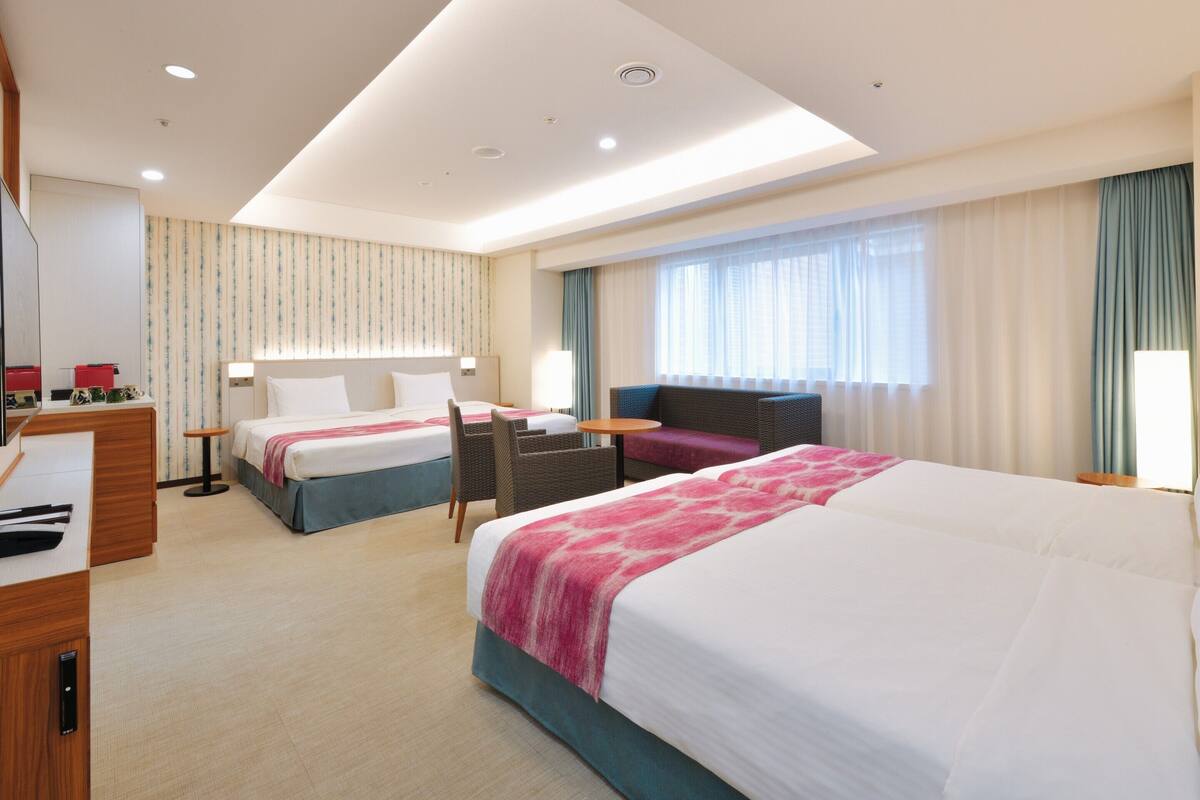 Una habitación de hotel con dos camas, un escritorio y una zona de estar.