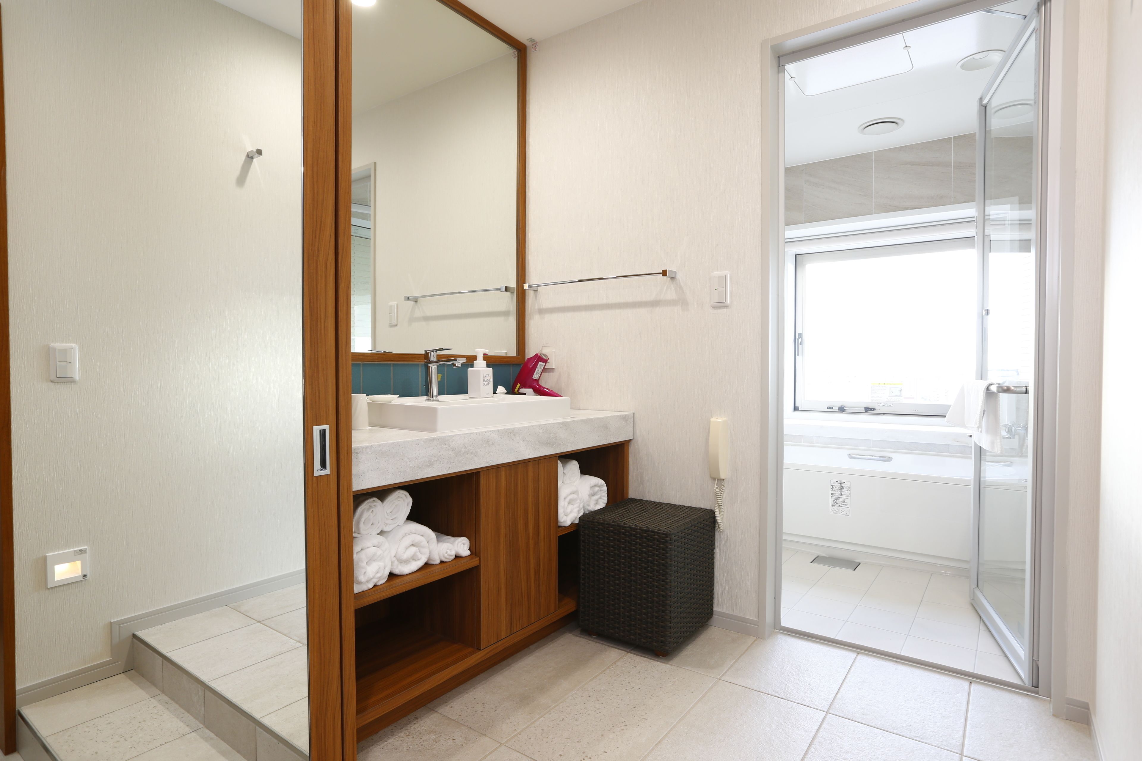 Un baño moderno con tocador de madera, cabina de ducha de vidrio y inodoro a la vista.