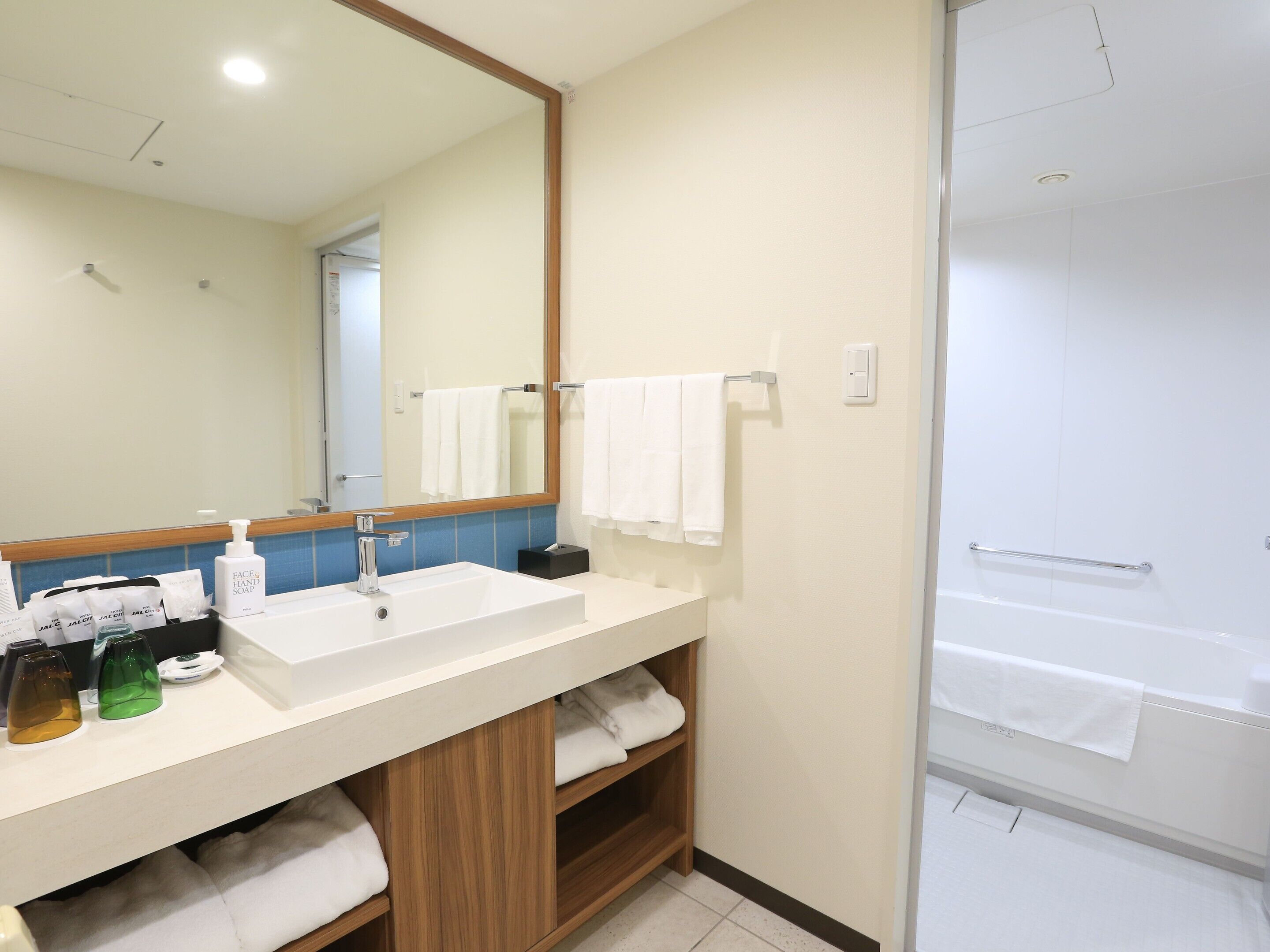 A modern bathroom with a large mirror, white sink, and a shower area.