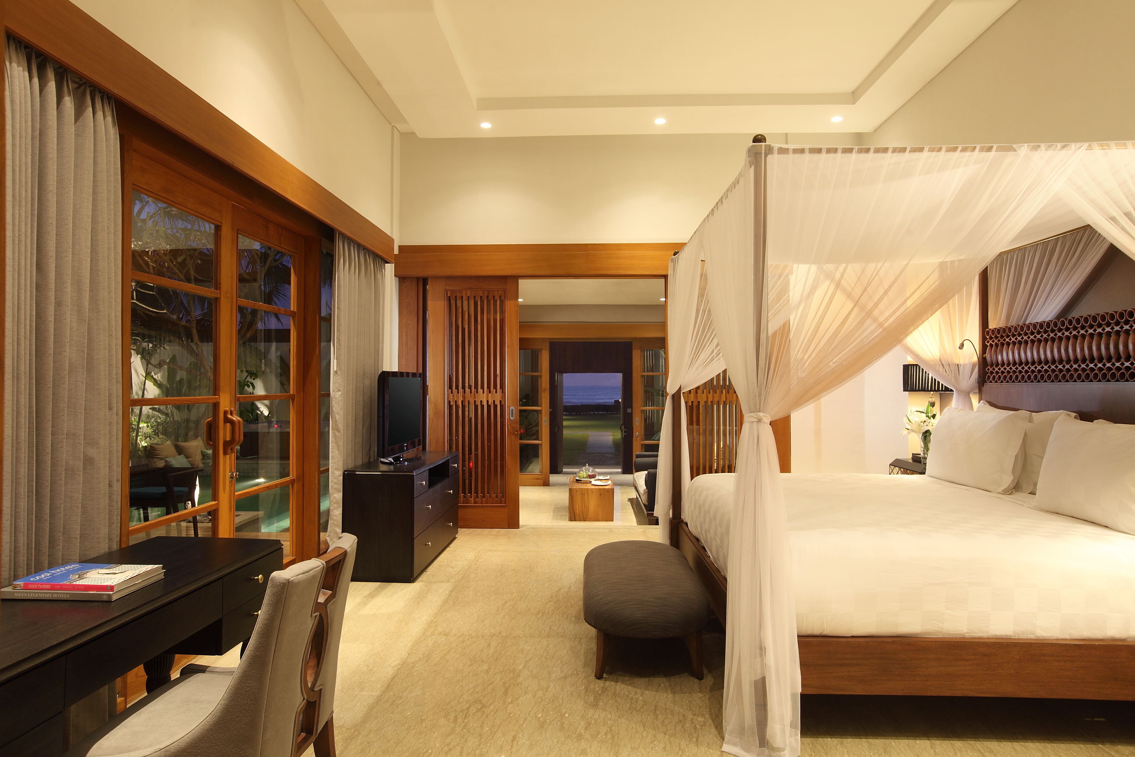 A bedroom with a four-poster bed, a desk with a chair, and a television.