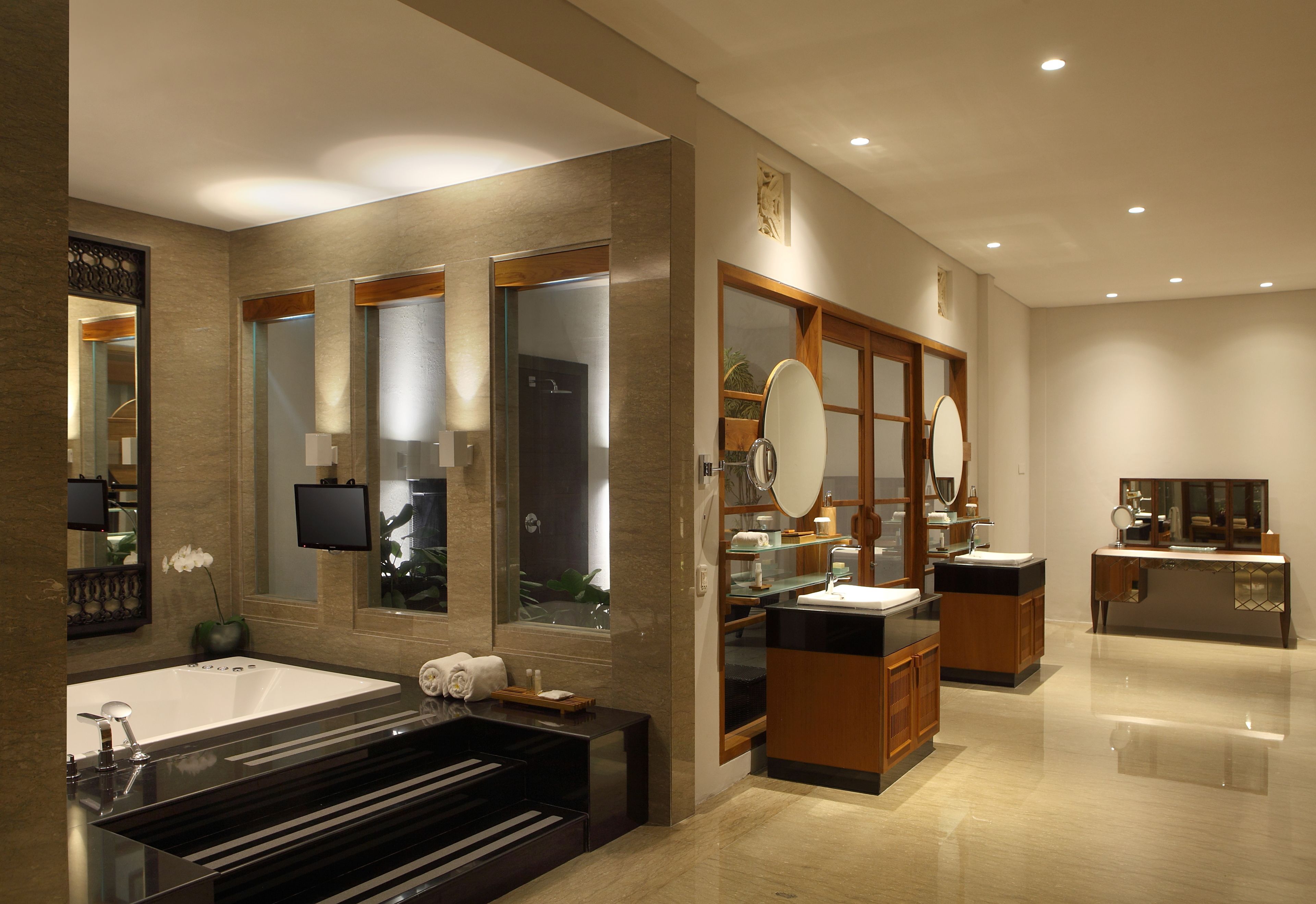 A modern bathroom with a large bathtub, a vanity with a mirror, and a separate sink area.
