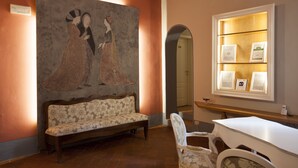 A room with a sofa, a chair, a table, a framed artwork, and a wall-mounted display case with plaques. - Home in Florence (Florence)