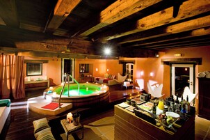Un área de spa con jacuzzi, vigas de madera, un mostrador de recepción con servicios y una zona de estar acogedora.
