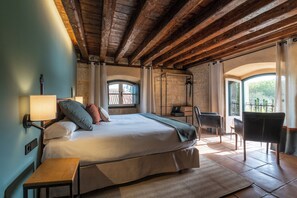 Une chambre à coucher comprenant un lit, une table de chevet, une lampe, une chaise et donnant sur l’extérieur.
