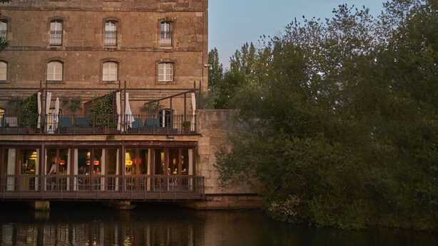 A historic building with a balcony overlooking a river.