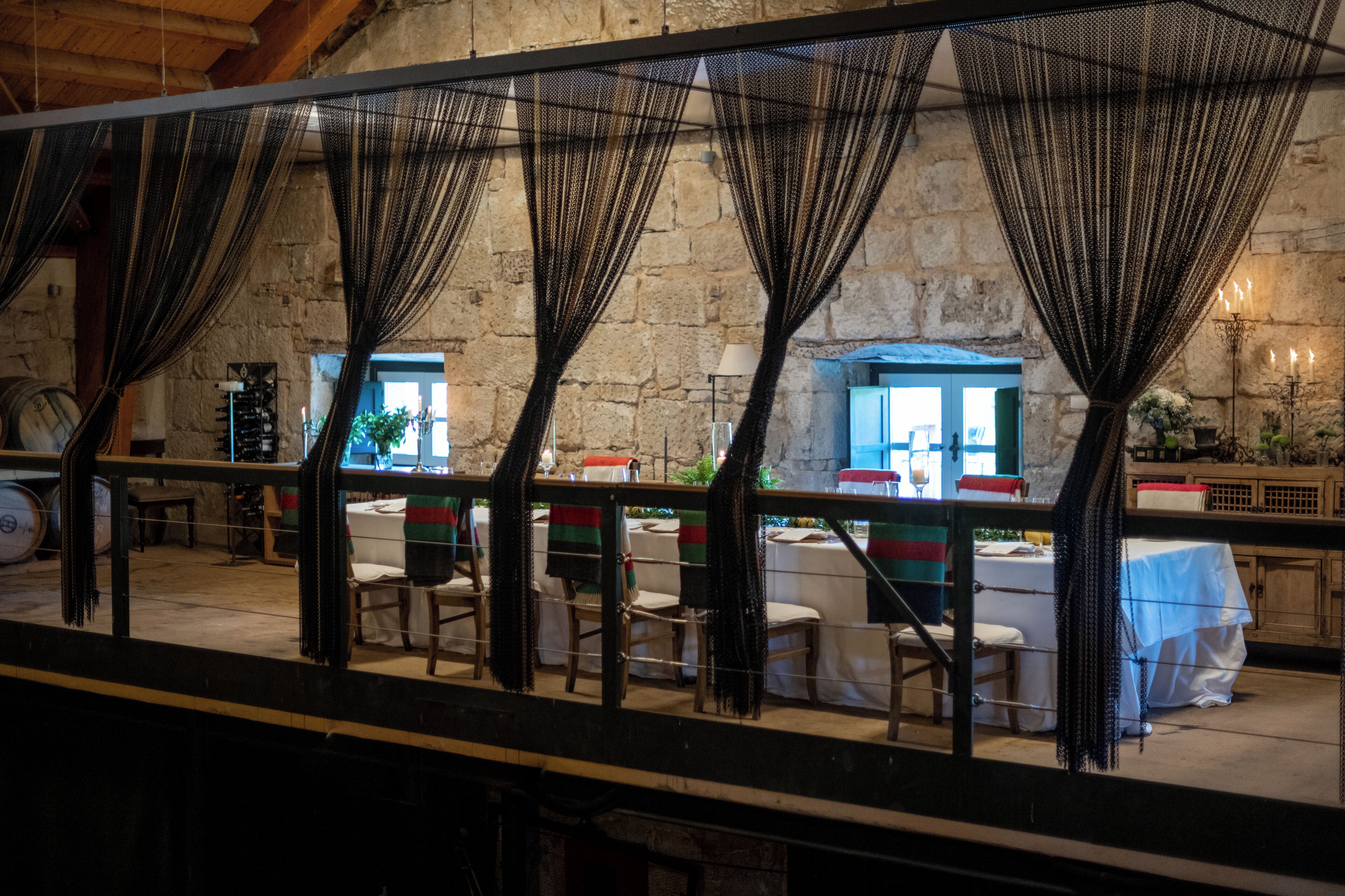 A restaurant with stone walls, tables with white tablecloths, and chairs.