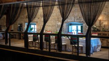 A restaurant with stone walls, tables with white tablecloths, and chairs.