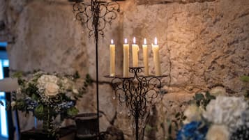Un candelabro con múltiples velas, una pared de piedra rústica y arreglos florales.