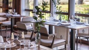 A restaurant with tables set for dining, large windows, and a view of the outdoors.