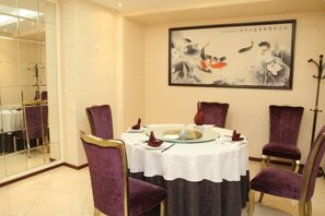 A dining area with a round table, purple chairs, and a painting on the wall. - Media Center Hotel (Beijing)