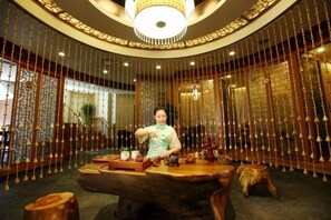 A traditional interior with a round table, wooden stools, and a person seated. - Media Center Hotel (Beijing)