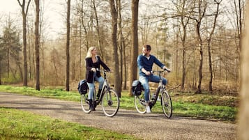 Dos personas andando en bicicleta por un camino de grava en un área boscosa.