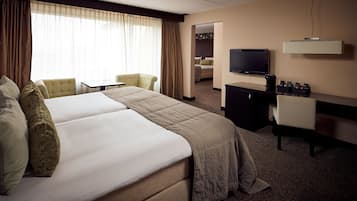 Een hotelkamer met een groot bed, een bureau met een computer, een televisie en een zithoek met stoelen.