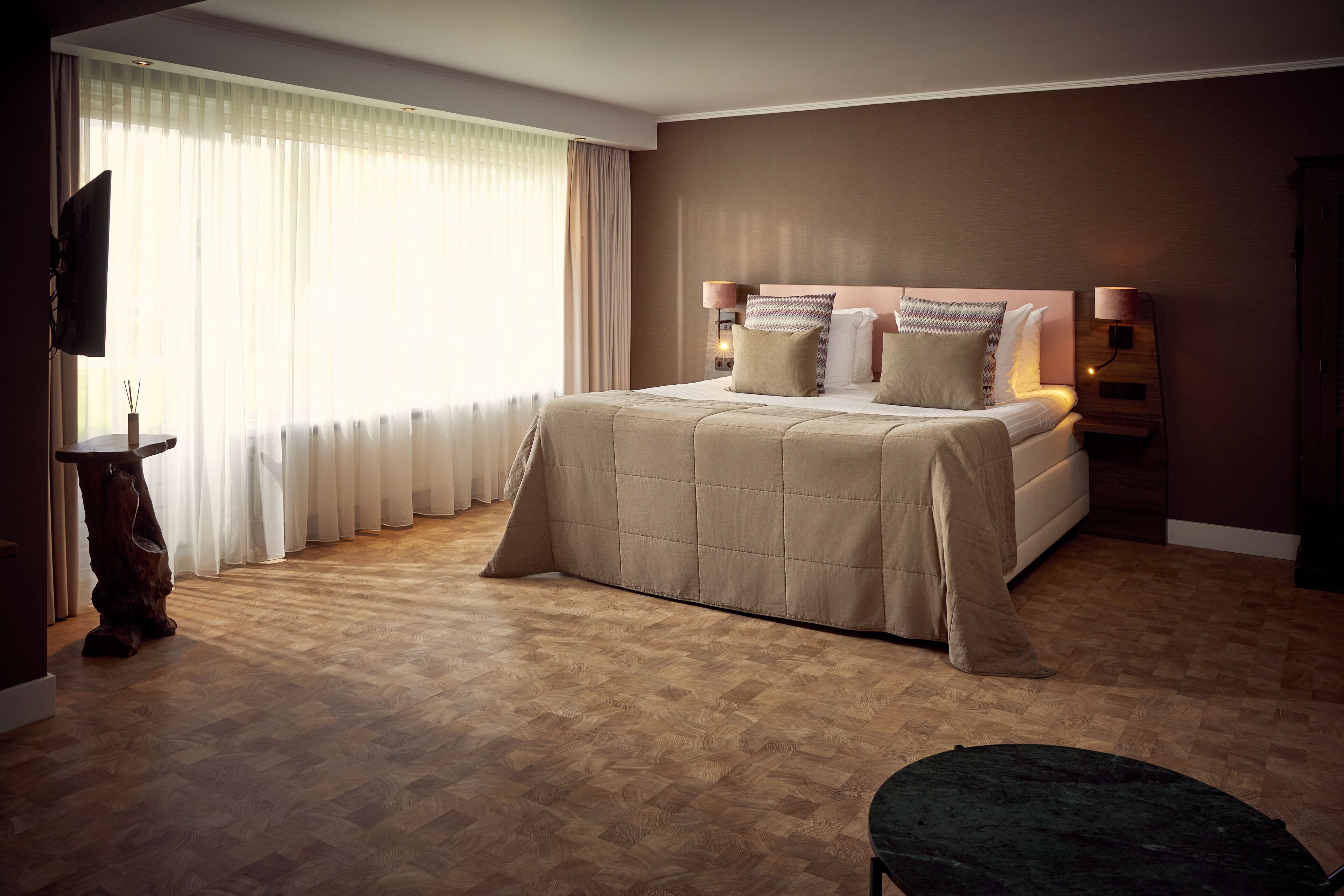 A bedroom with a large bed, a TV, and a wooden floor.