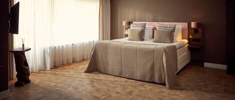 Un dormitorio con una cama grande, televisión y suelo de madera.