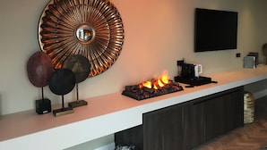 Eine moderne Küche mit einer zentralen Kochinsel, einem großen Dekospiegel und einem eingebauten Kamin.