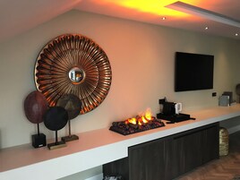Una cocina moderna con una isla central, un espejo decorativo grande y una chimenea empotrada.