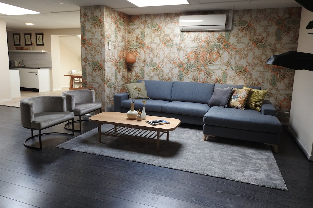 Un salon moderne avec un canapé, des fauteuils et une table basse.