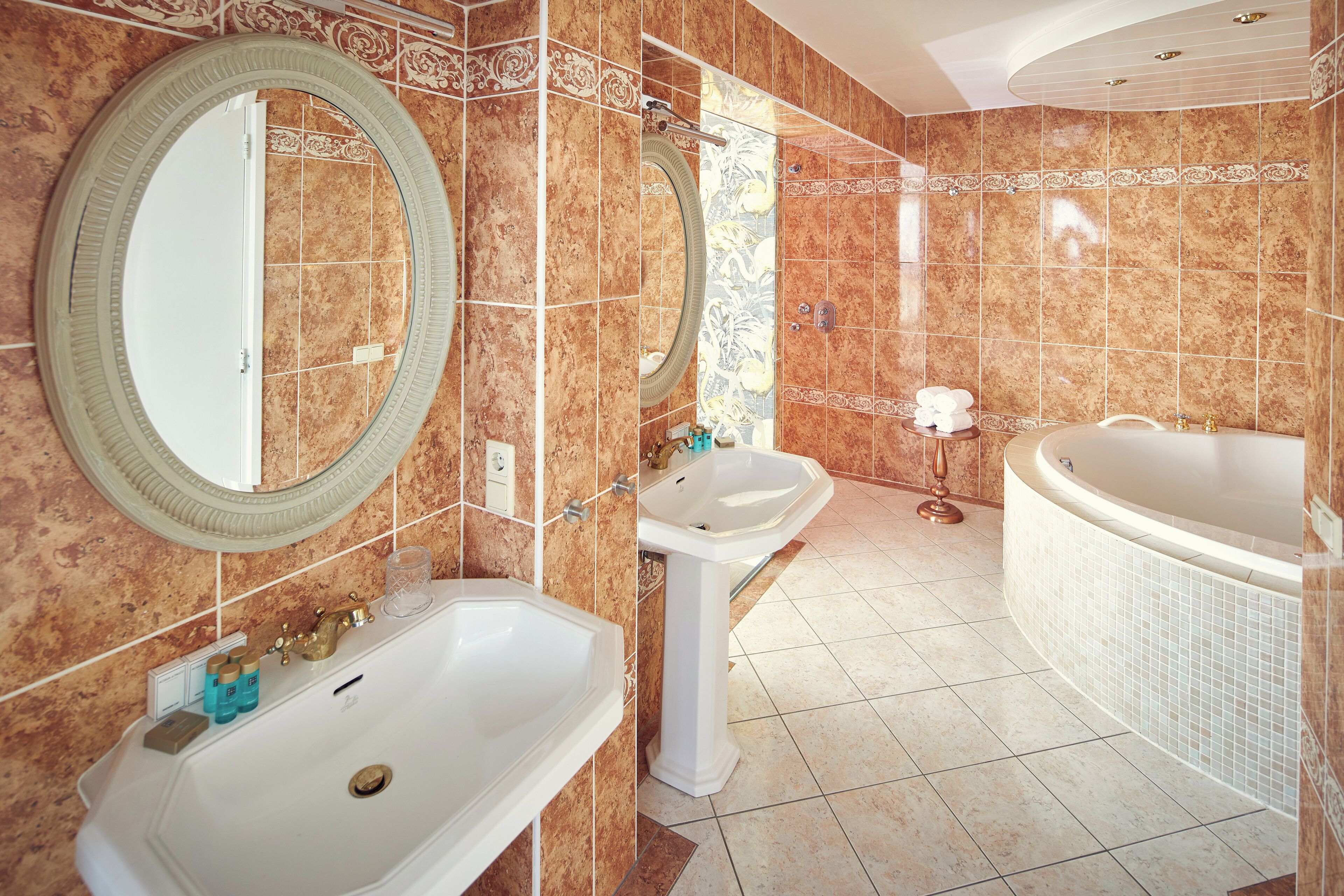 Un baño con una bañera grande, dos lavamanos y tres espejos.