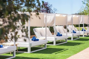 A row of white lounge chairs with beige canopies, arranged on a green lawn. - Hotel HSM Atlantic Park Hotel (Calvia)
