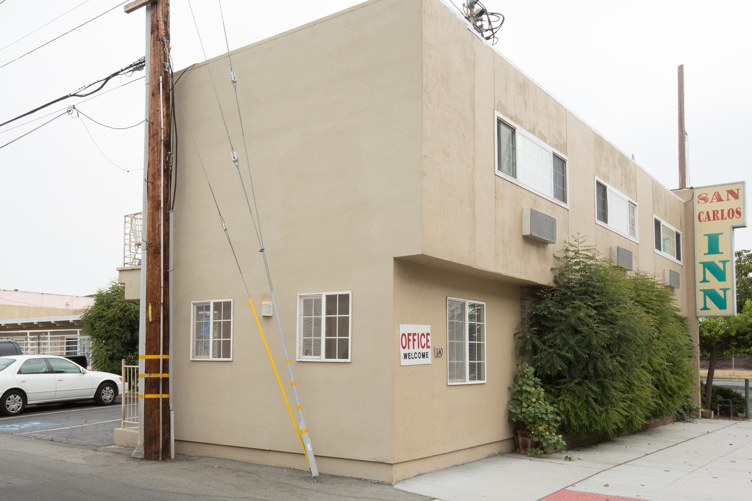 A beige building with a sign reading "SAN CARLOS INN" and "OFFICE WELCOME."