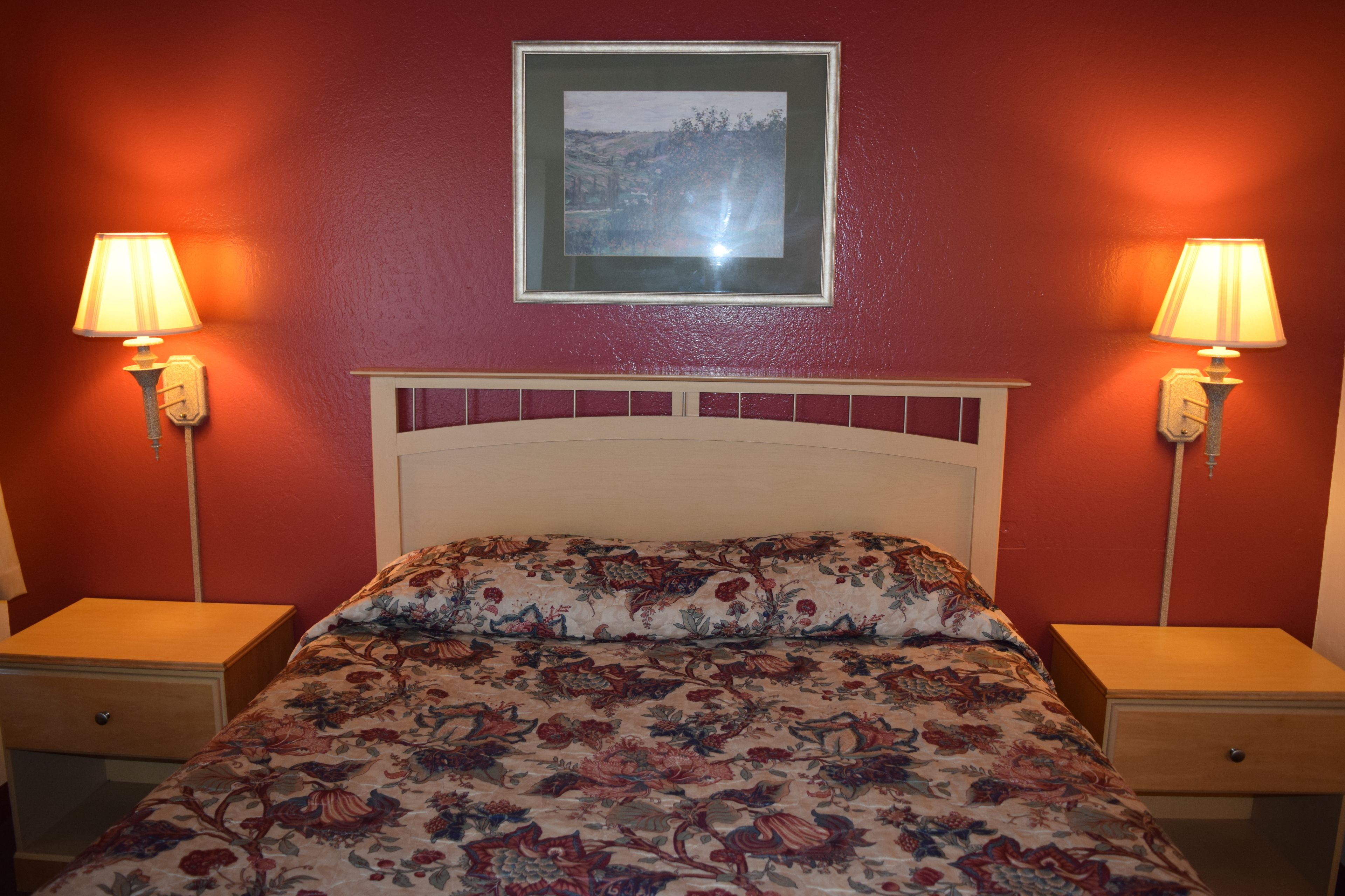 Quarto com cama, duas mesas de cabeceira e duas luminárias de parede.