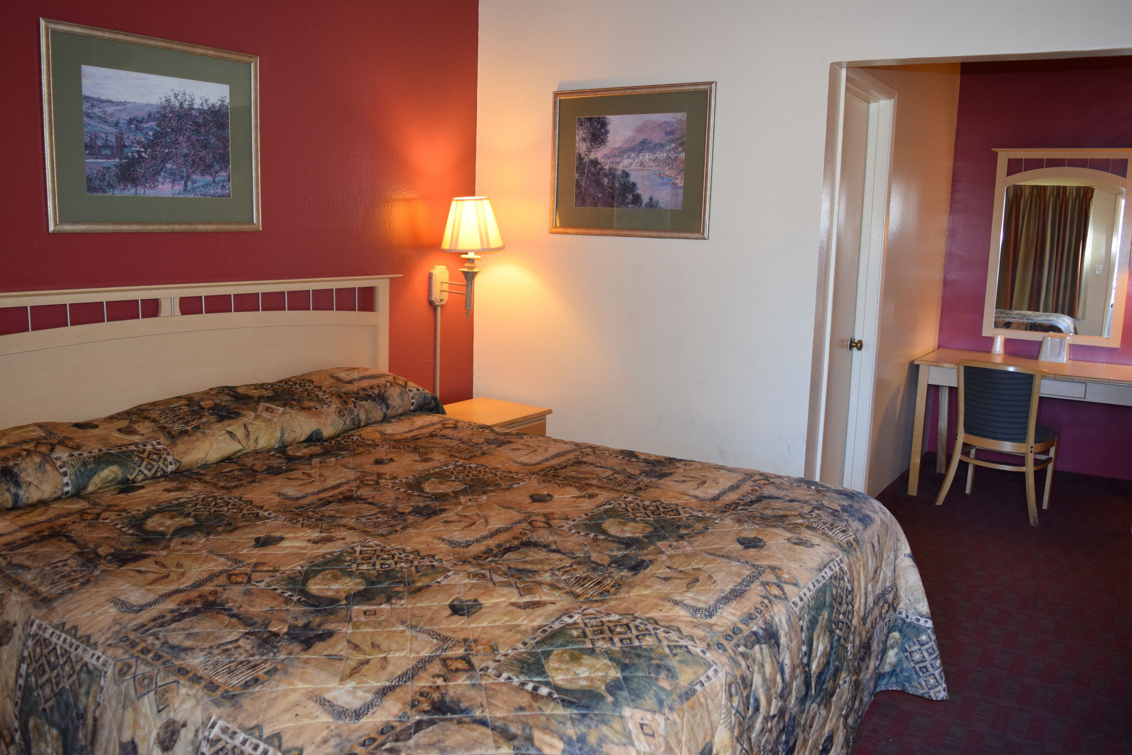 Une chambre d’hôtel avec un grand lit, un bureau avec une chaise et deux tableaux encadrés au mur.