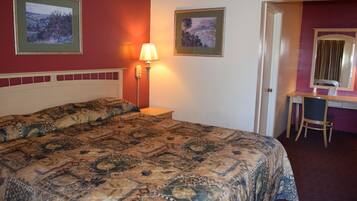 Une chambre d’hôtel avec un grand lit, un bureau avec une chaise et deux tableaux encadrés au mur.