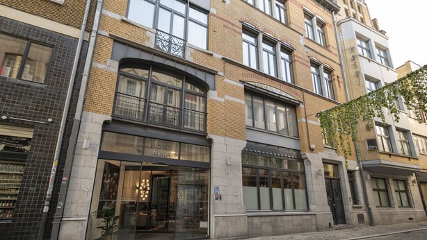 Et hotel med en klassisk facade, store vinduer og en tydelig indgang.
