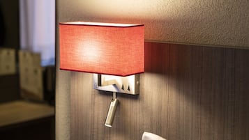A wall-mounted lamp with a red shade in a hotel room.