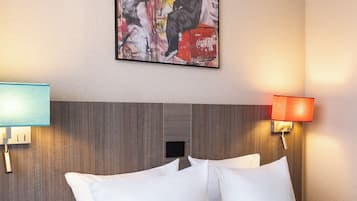 Ein Hotelzimmer mit einem großen Bett, weißen Kissen, einem Holzausschlag am Kopfteil, zwei Wandlampen und einem Poster an der Wand.