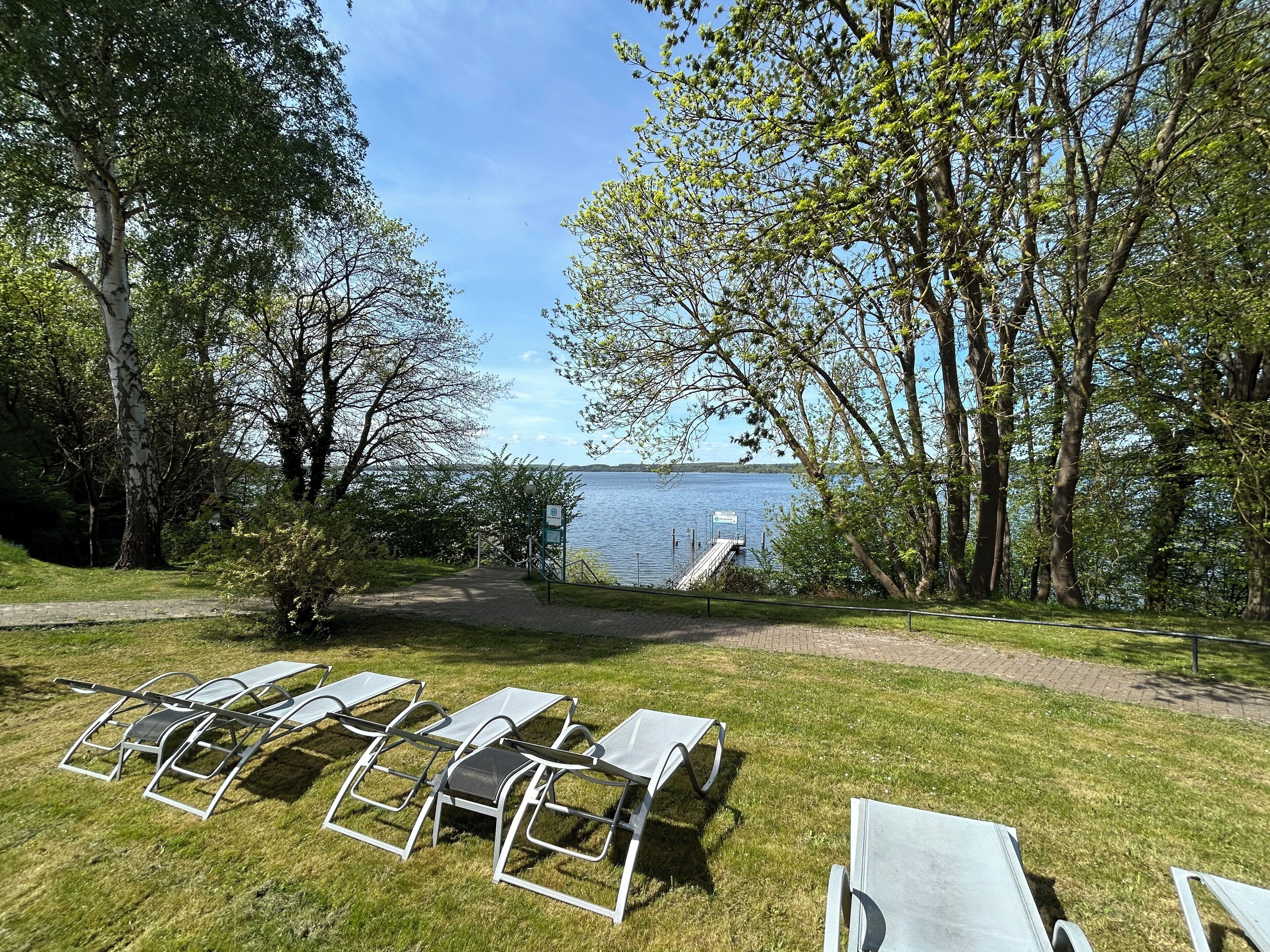 A lakeside outdoor seating area with metal chairs and a wooden deck.