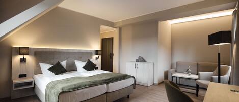Una habitación de hotel moderna con una cama, un escritorio, una silla, un armario y una lámpara.