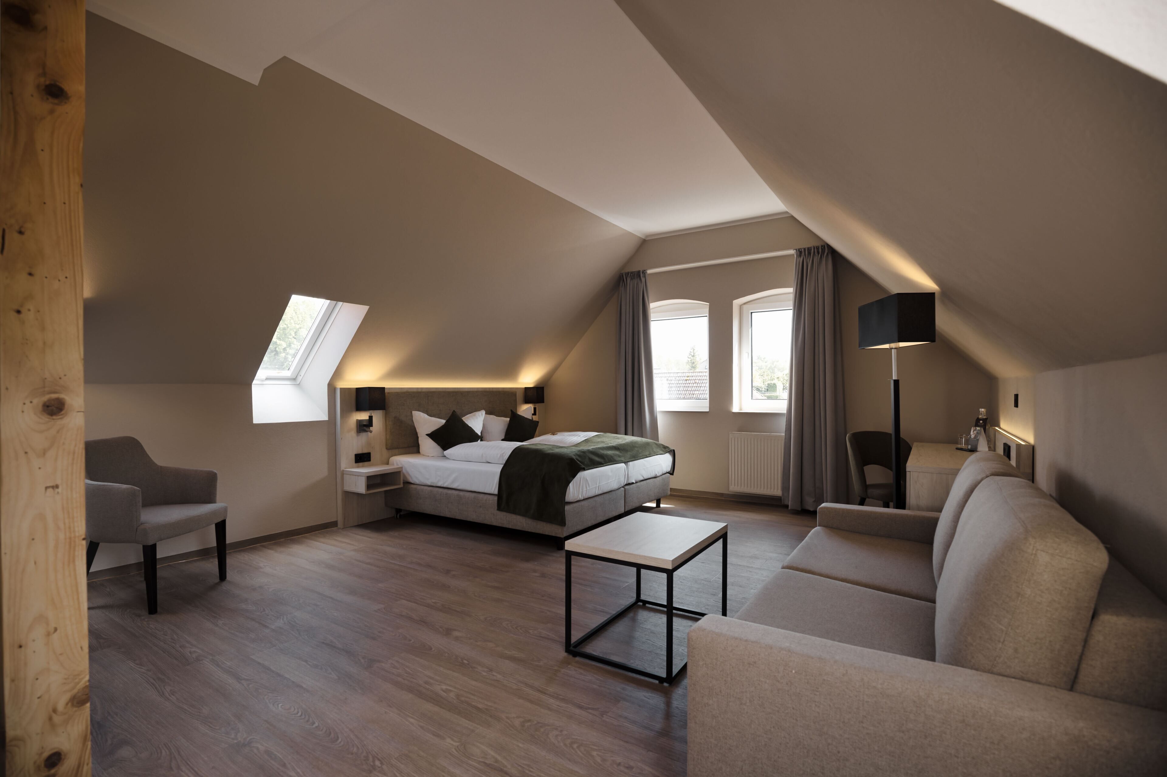 Un dormitorio estilo loft moderno con tragaluces, cama, sofá, una mesa de centro y un escritorio.