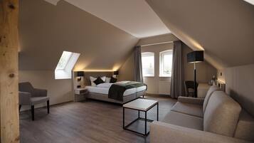 A modern loft bedroom with a skylight, a bed, a sofa, a coffee table, and a desk.