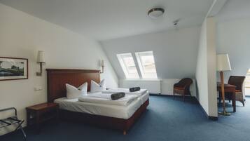 Ein Schlafzimmer mit einem hölzernen Bett, zwei Nachttischen, einem Sessel, einem Schreibtisch und einem Fenster.