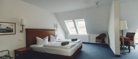 Un dormitorio con una cama de madera, dos mesitas de noche, una silla, un escritorio y una ventana.