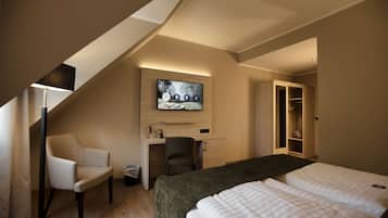 A hotel room with a bed, desk, chair, TV, and wardrobe.