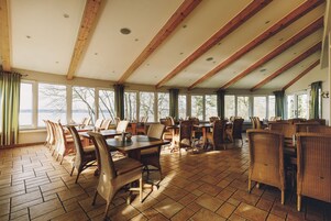 A spacious dining area with wooden tables and chairs, large windows offering views of the outdoors.