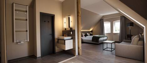 En moderne lejlighed i loftstil med en alkove, et tekøkken, et badeværelse med håndvask og et siddeområde med sofa og sofabord.