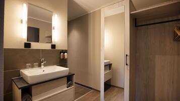 A modern bathroom with a large mirror, a sink, and a wooden vanity.