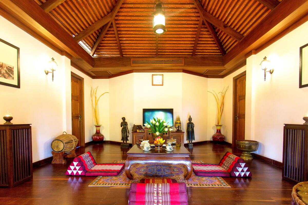 A spacious room with a wooden ceiling, a television, and a central table with decorative items.